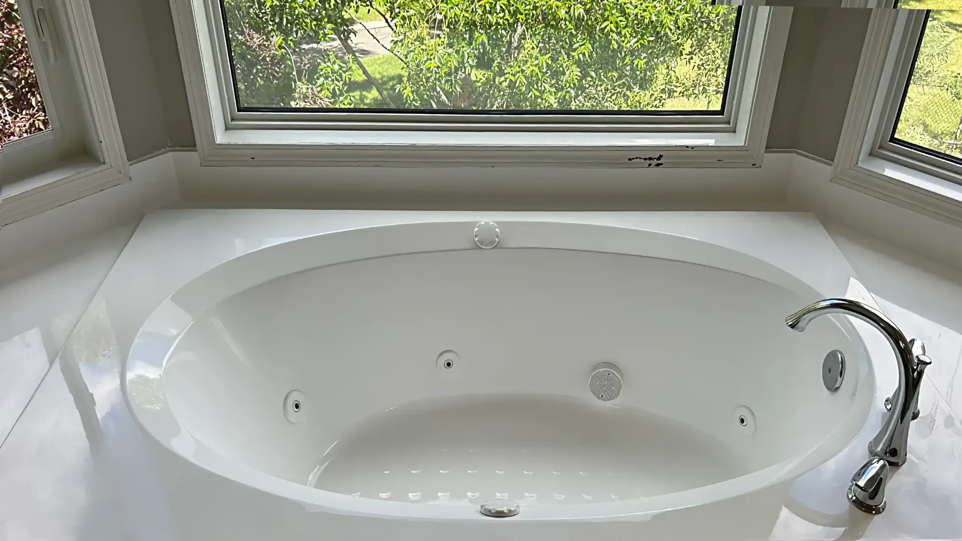 Refinished white bathtub in a bright bay-window bathroom